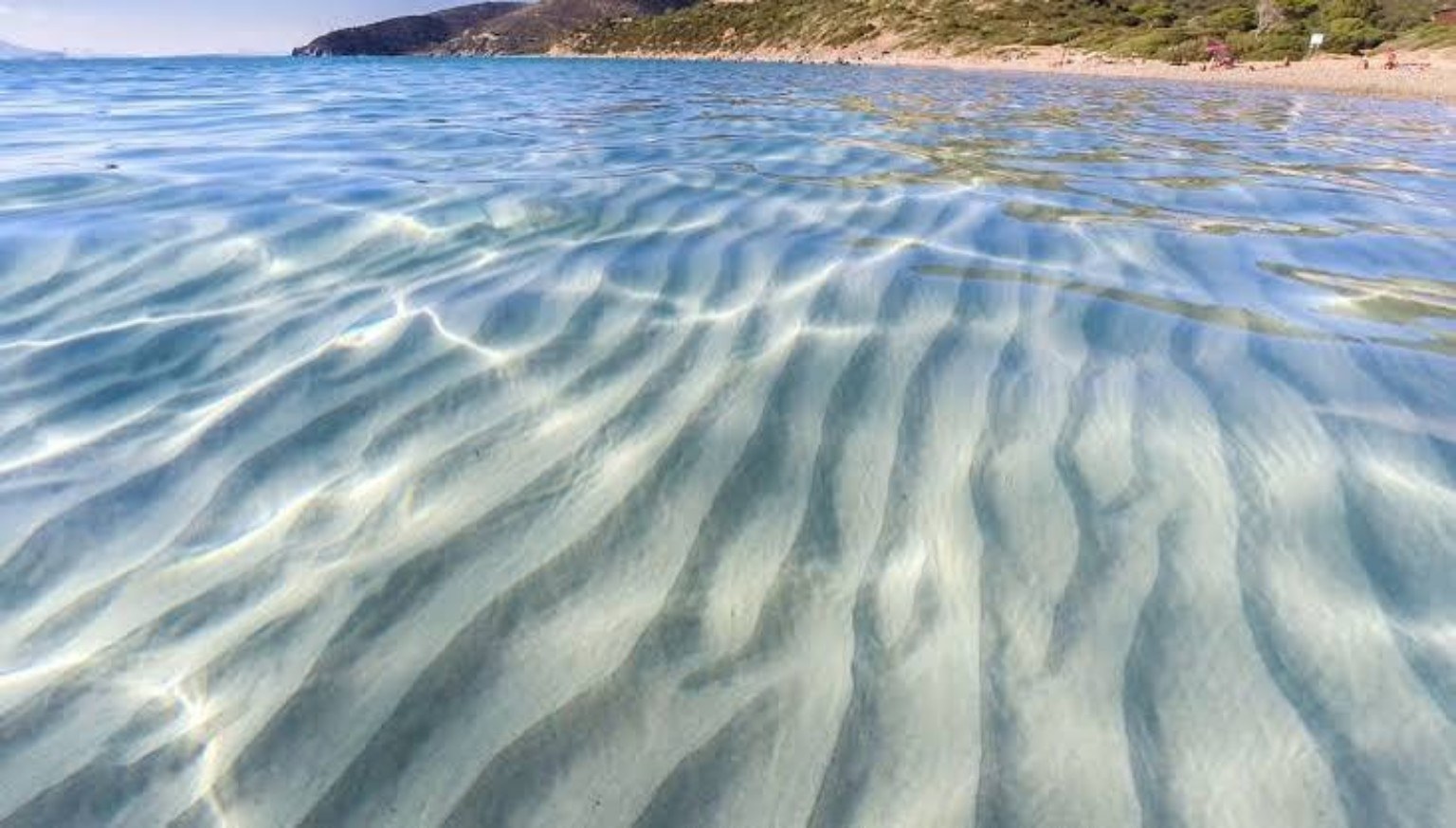 Agua transparente y reflejos del sol junto a una costa italiana
